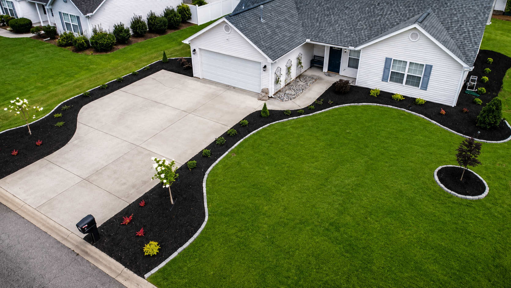 Freshly landscaped driveway with curved black mulch beds and new plantings