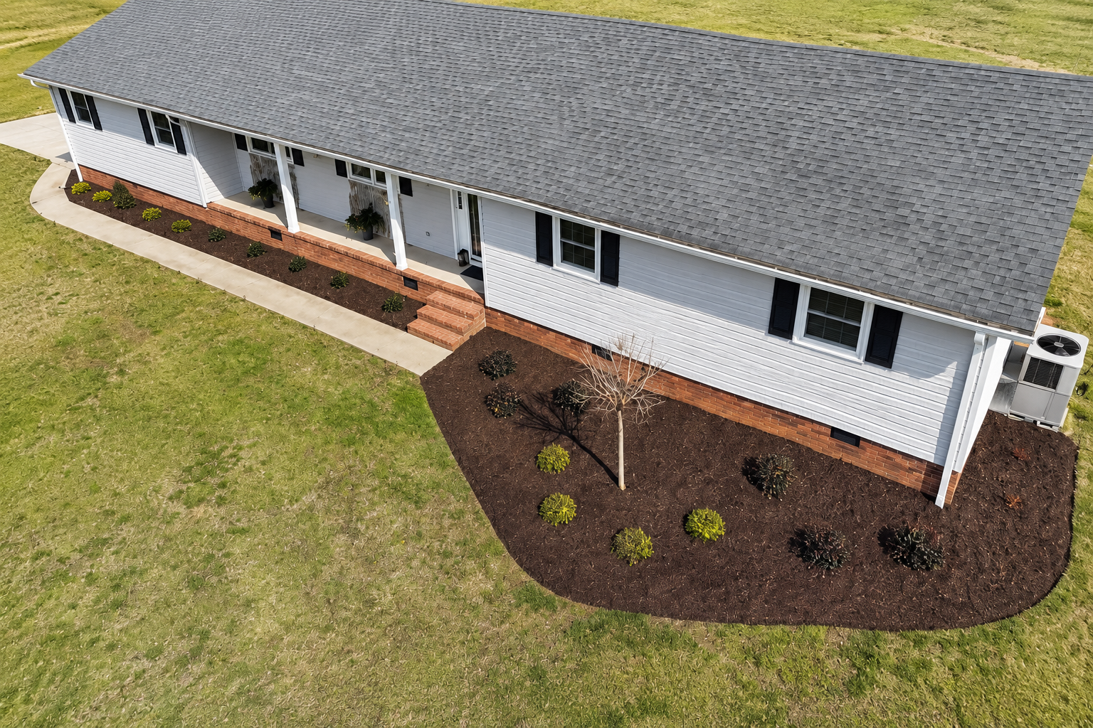 Aerial view of fresh sod, flowing dark mulch beds, and a stone walkway